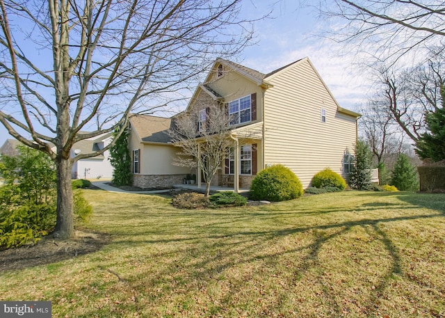 view of side of home featuring a patio area, stone siding, stucco siding, and a yard