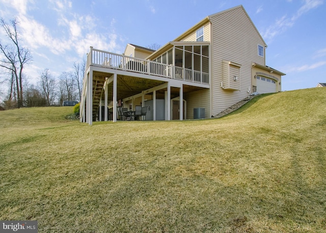 rear view of house featuring a wooden deck, a lawn, central AC, and a sunroom