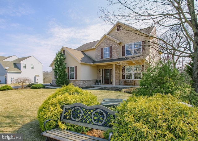 view of front of property featuring stucco siding, stone siding, and a front lawn