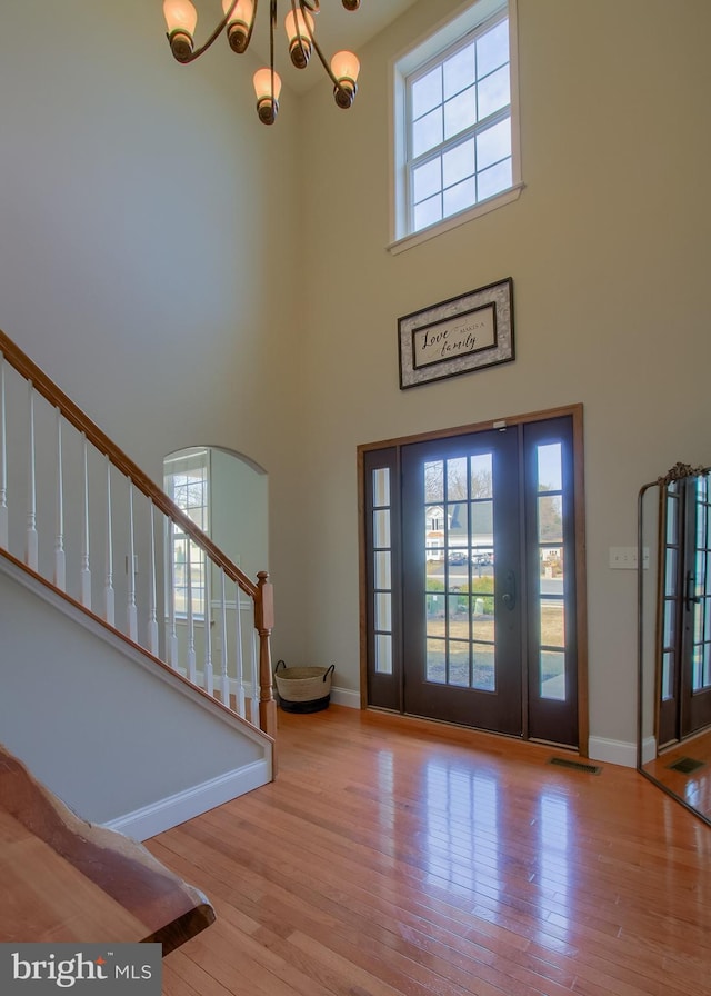 foyer featuring stairs, an inviting chandelier, baseboards, and wood-type flooring