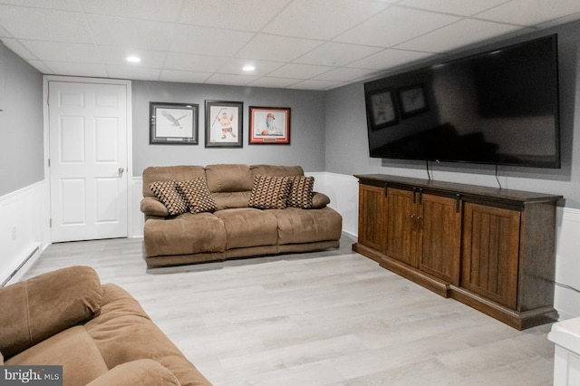 living room with a paneled ceiling, a baseboard heating unit, and light wood-type flooring