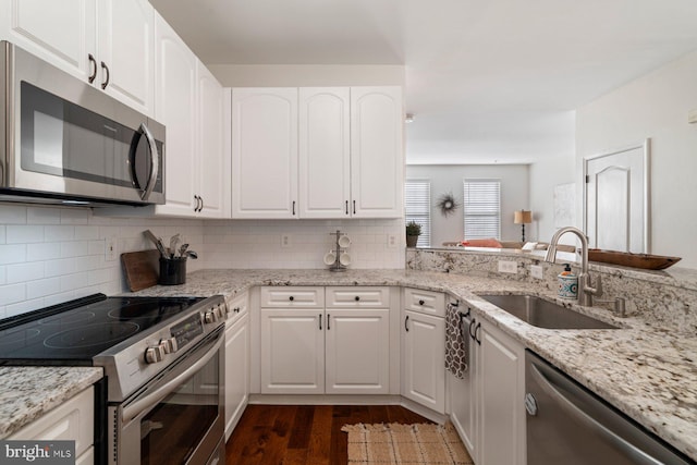 kitchen featuring sink, stainless steel appliances, light stone counters, white cabinets, and decorative backsplash