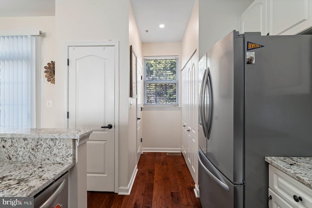 kitchen featuring dark wood-type flooring, light stone counters, white cabinets, and stainless steel refrigerator