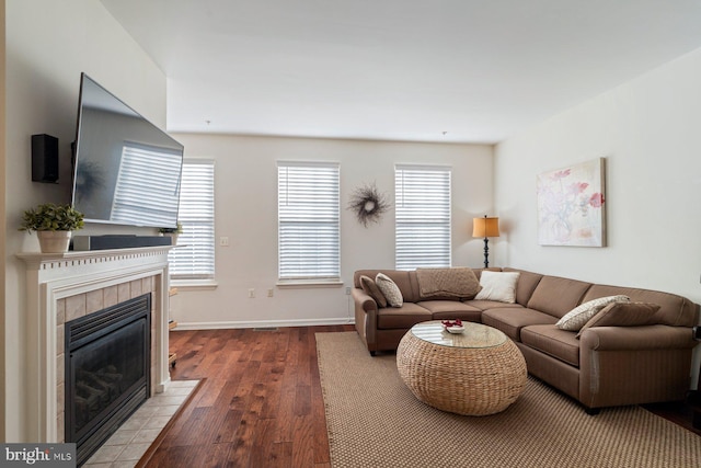 living room with a tiled fireplace, plenty of natural light, and hardwood / wood-style flooring