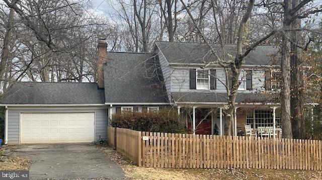 view of front of home with aphalt driveway, an attached garage, a chimney, and a fenced front yard