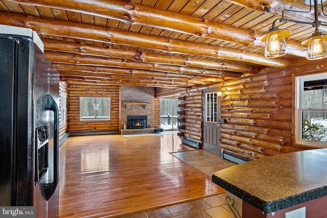 unfurnished living room with wooden ceiling, a brick fireplace, beam ceiling, rustic walls, and a baseboard radiator