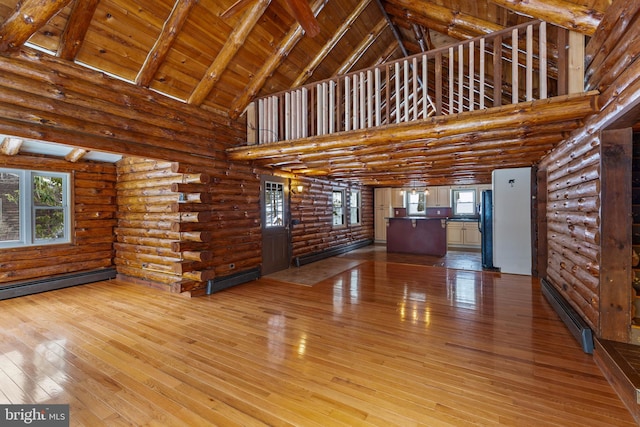 unfurnished living room featuring wooden ceiling, hardwood / wood-style floors, high vaulted ceiling, log walls, and beam ceiling