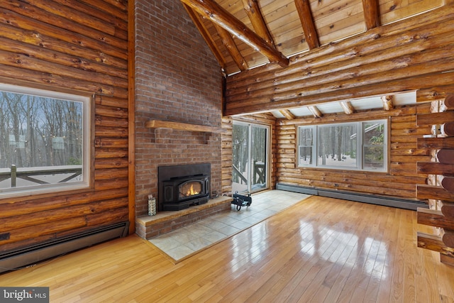 unfurnished living room featuring baseboard heating, high vaulted ceiling, a wood stove, and rustic walls