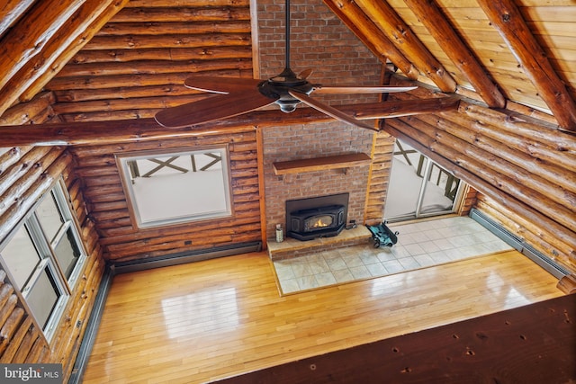 unfurnished living room featuring light wood-type flooring, log walls, ceiling fan, a wood stove, and a baseboard radiator