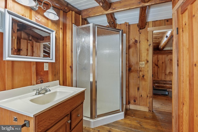 bathroom with beam ceiling, vanity, wood walls, and a shower with shower door