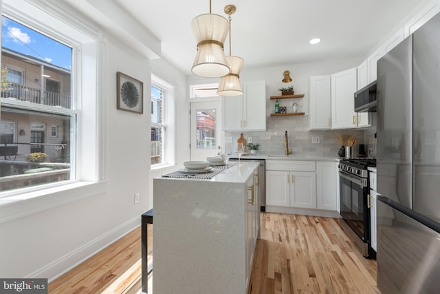 kitchen featuring pendant lighting, sink, decorative backsplash, appliances with stainless steel finishes, and white cabinetry