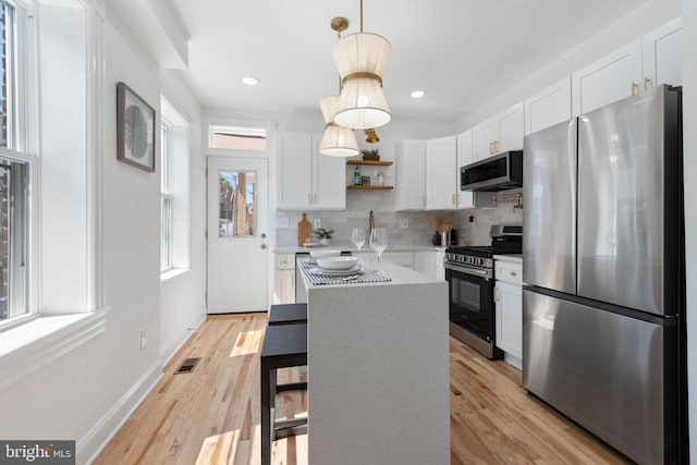 kitchen with decorative light fixtures, white cabinetry, appliances with stainless steel finishes, and tasteful backsplash