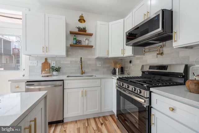 kitchen featuring white cabinets, light stone countertops, sink, and appliances with stainless steel finishes