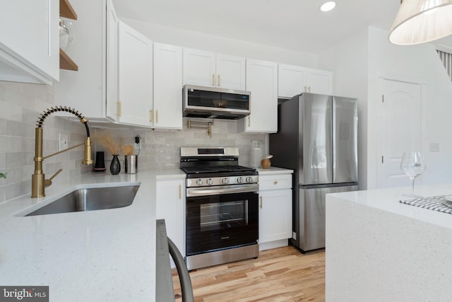 kitchen with white cabinets, decorative backsplash, sink, and stainless steel appliances