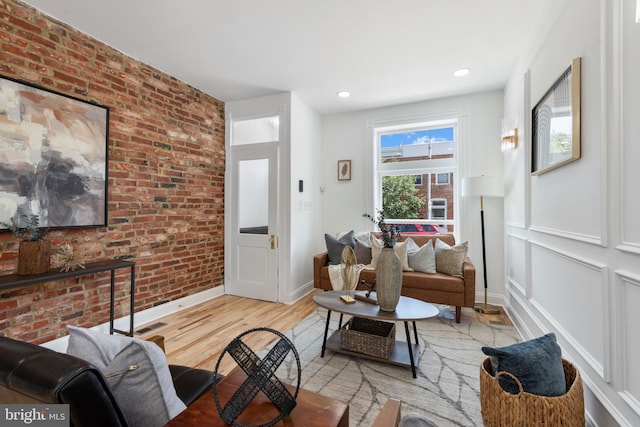 living room with light wood-type flooring and brick wall