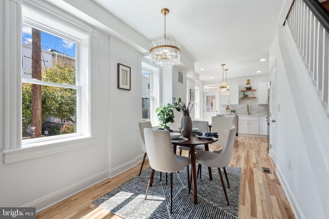 dining room featuring light wood-type flooring, an inviting chandelier, and a wealth of natural light