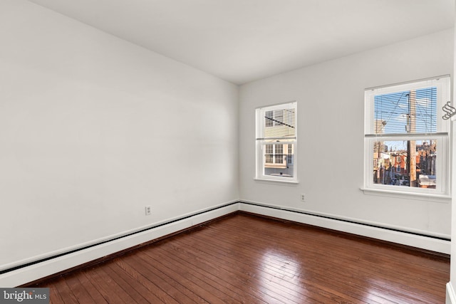 spare room featuring baseboard heating and hardwood / wood-style floors