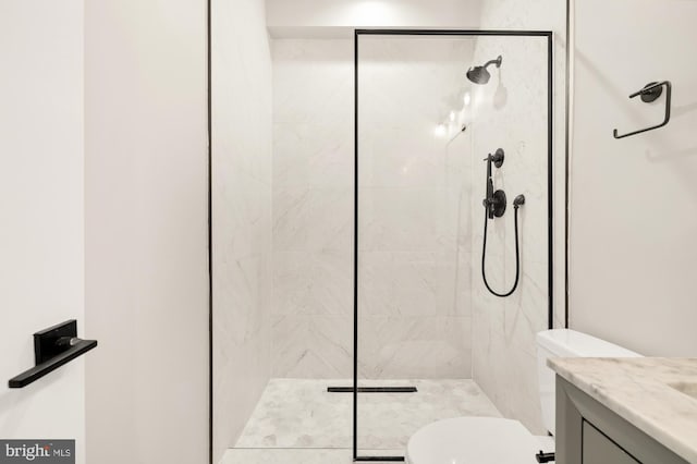 bathroom with toilet, vanity, and tiled shower