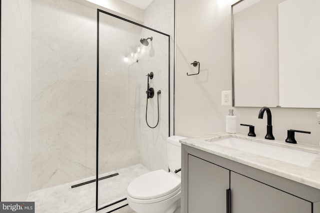 bathroom featuring toilet, vanity, and a tile shower