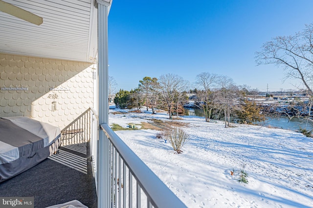 snow covered back of property with a water view