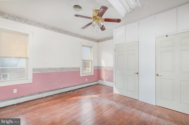 unfurnished bedroom with ceiling fan, hardwood / wood-style flooring, visible vents, and a baseboard radiator