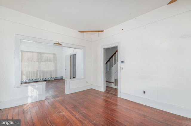 empty room with visible vents, stairs, and hardwood / wood-style flooring