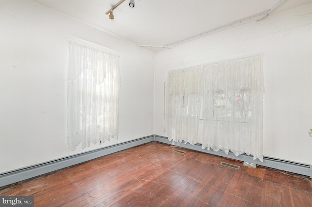 spare room with a baseboard radiator, wood-type flooring, visible vents, and track lighting