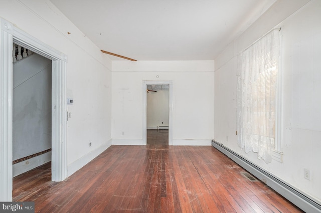 empty room with a wealth of natural light, a baseboard radiator, and hardwood / wood-style floors