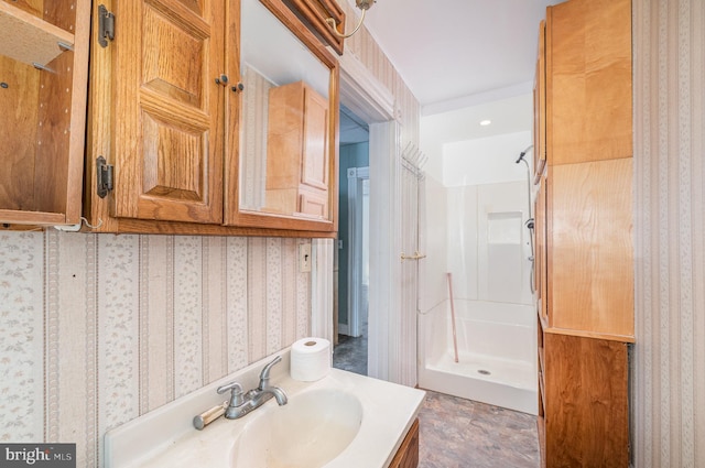 bathroom with vanity, a shower stall, and wallpapered walls