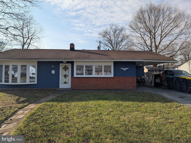 ranch-style home featuring a carport, brick siding, a chimney, and a front lawn