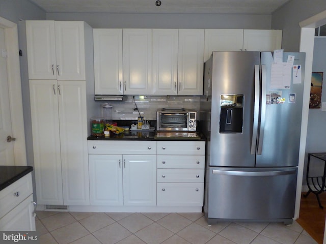 kitchen with stainless steel refrigerator with ice dispenser, backsplash, white cabinetry, and light tile patterned floors