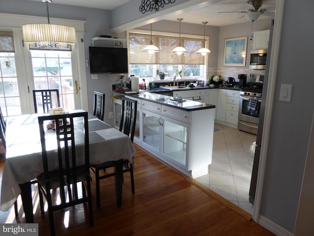 kitchen featuring white cabinets, sink, stainless steel appliances, and hanging light fixtures