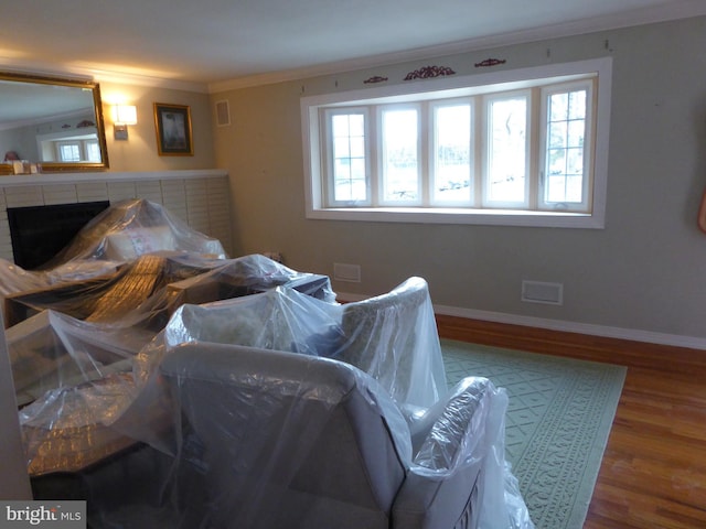 bedroom featuring hardwood / wood-style floors, ornamental molding, and a fireplace