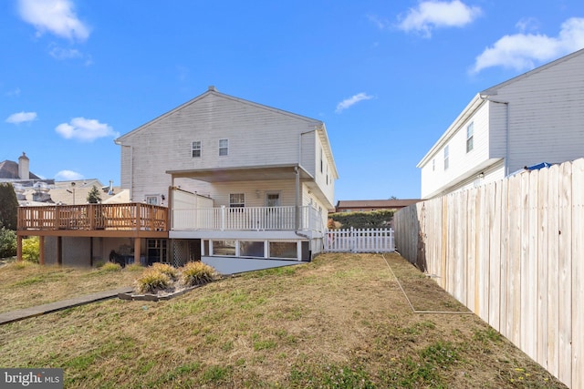 rear view of house with a lawn and a wooden deck