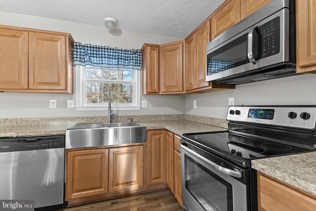 kitchen with stainless steel appliances, sink, a textured ceiling, and dark hardwood / wood-style floors