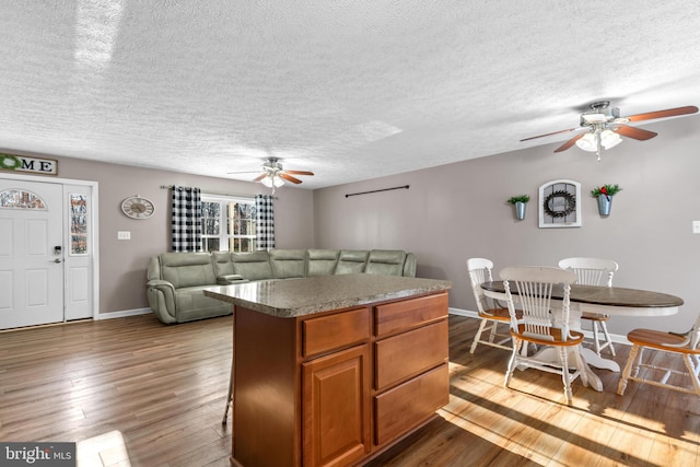 kitchen with hardwood / wood-style floors, a center island, and ceiling fan