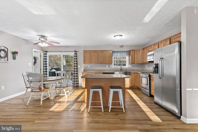 kitchen featuring a wealth of natural light, a breakfast bar area, a center island, and appliances with stainless steel finishes