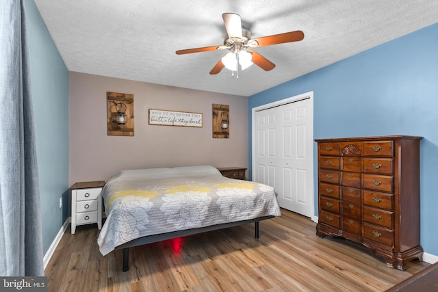 bedroom with ceiling fan, wood-type flooring, a closet, and a textured ceiling