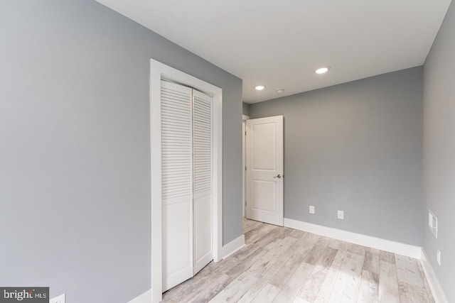 unfurnished bedroom with light wood-type flooring and a closet