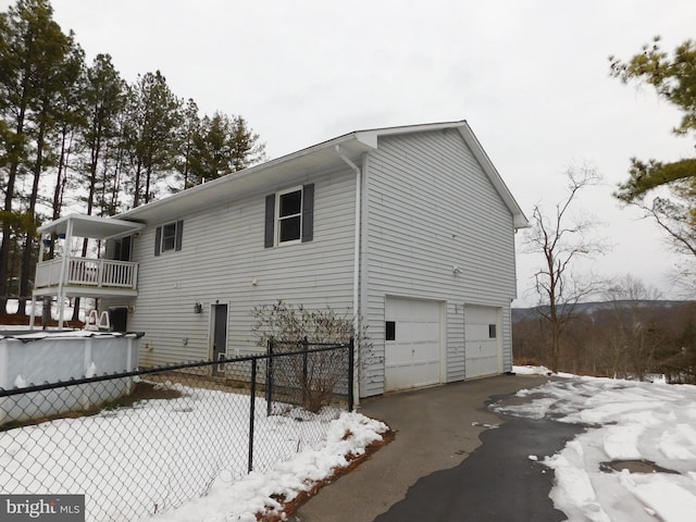 view of snow covered exterior with a balcony and a garage