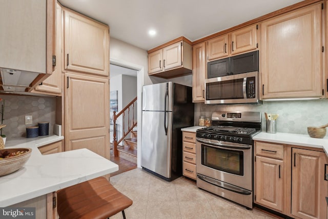 kitchen with decorative backsplash, light tile patterned floors, stainless steel appliances, and a breakfast bar area