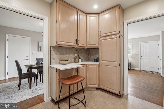 kitchen with light brown cabinets and tasteful backsplash