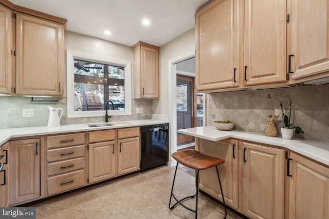 kitchen featuring a breakfast bar area, black dishwasher, light brown cabinets, tasteful backsplash, and sink