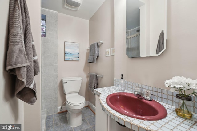 bathroom featuring toilet, a shower, decorative backsplash, and sink