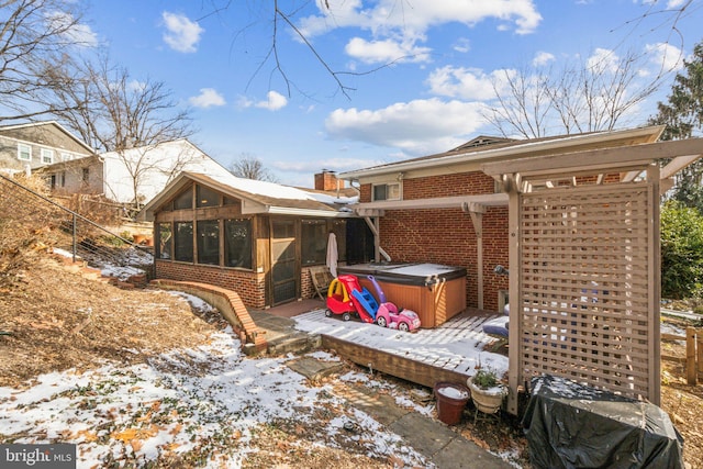 snow covered property with a hot tub and a sunroom