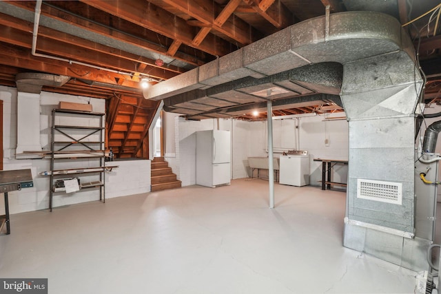 basement featuring sink, washer / dryer, and white refrigerator