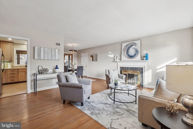 living room featuring a brick fireplace, a chandelier, and light hardwood / wood-style floors