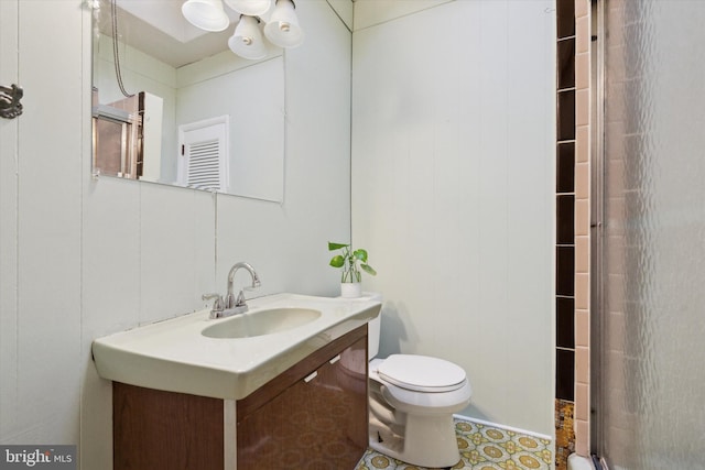 bathroom featuring vanity, a shower with shower door, and toilet