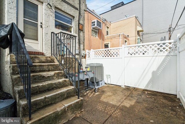 view of patio featuring a wall mounted air conditioner and central air condition unit