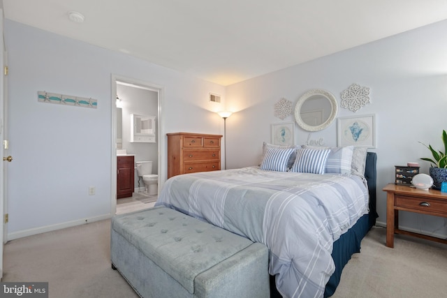 bedroom featuring ensuite bath and light colored carpet